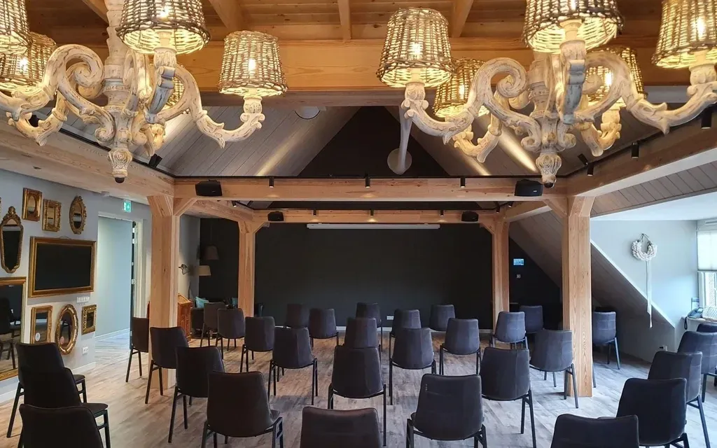 Een grote kamer met rijen stoelen en kroonluchters die aan het plafond hangen