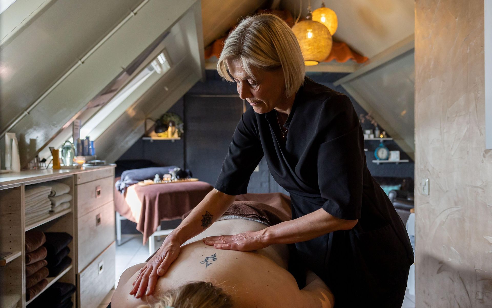 A woman is giving a massage to a man in an attic room.