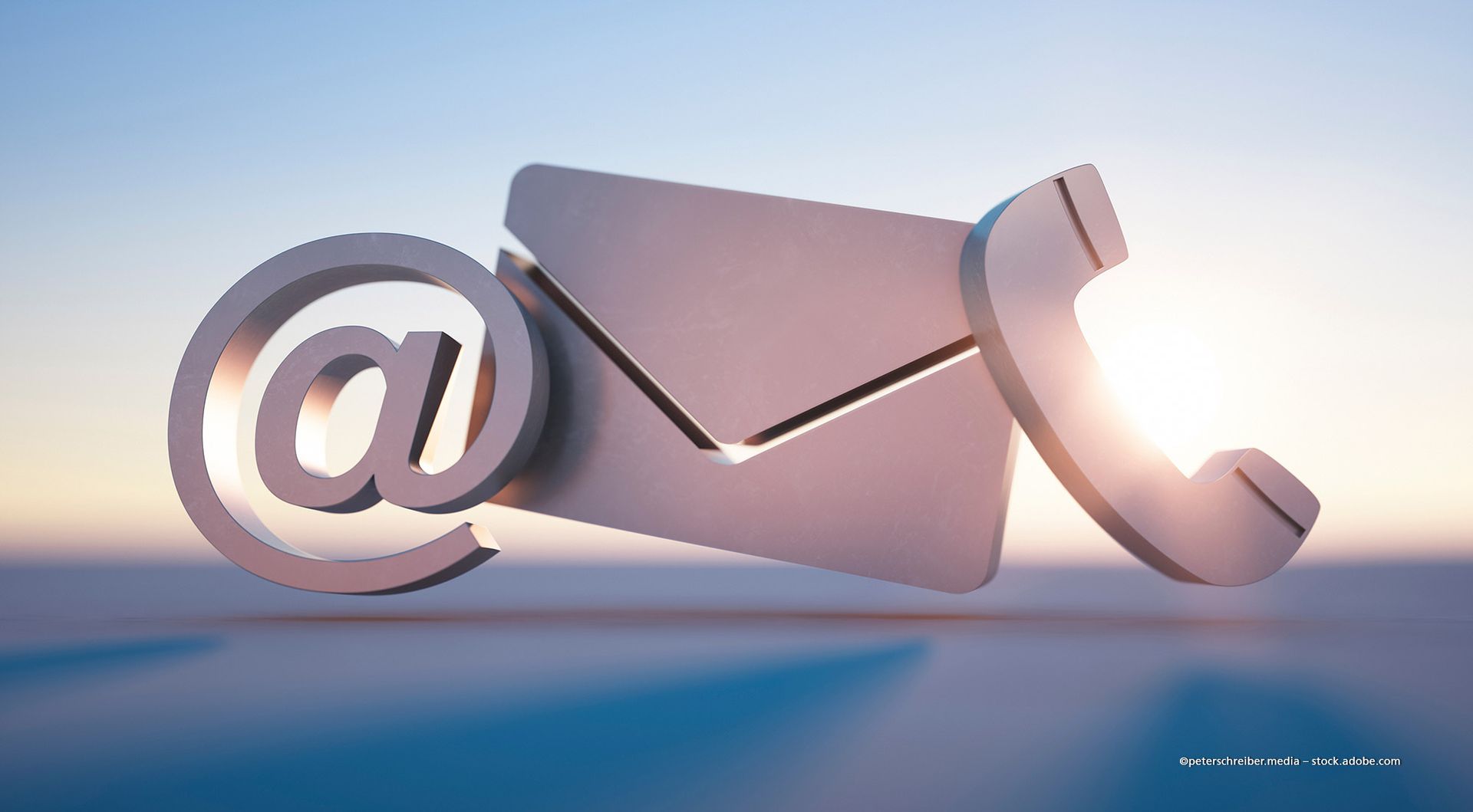 Silbernes E-Mail-Symbol, Umschlag und Telefonsymbol vor einem verschwommenen Himmel, die Kontaktoptionen darstellen.