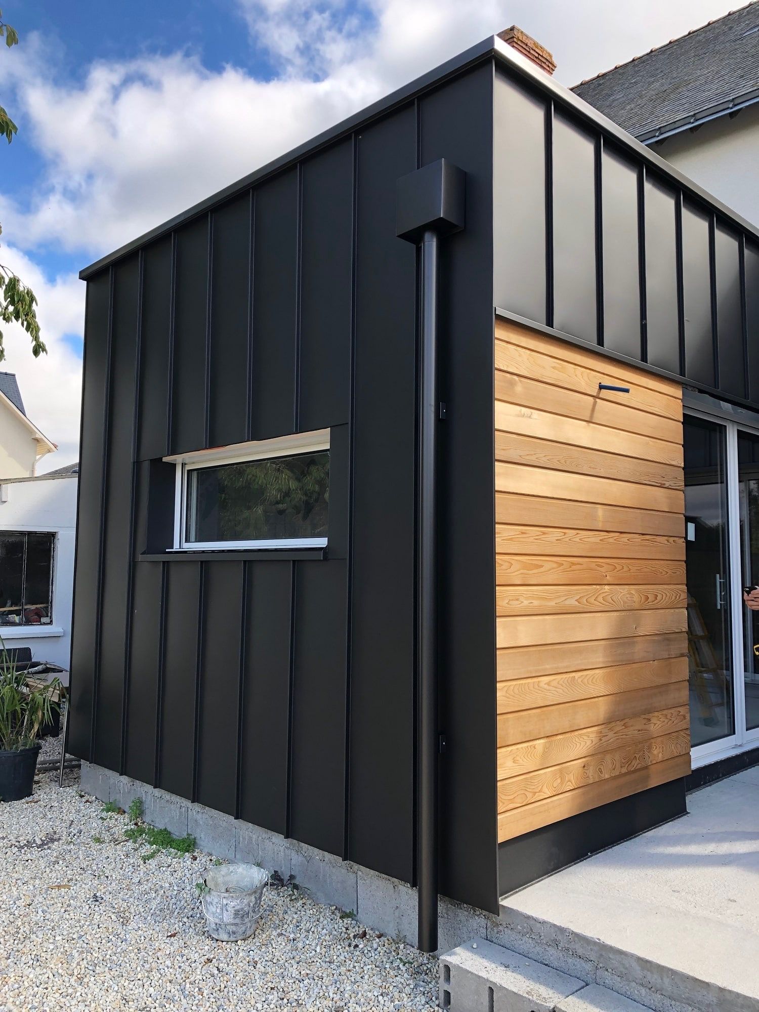 Maison moderne avec bardage noir avec une petite fenêtre horizontale