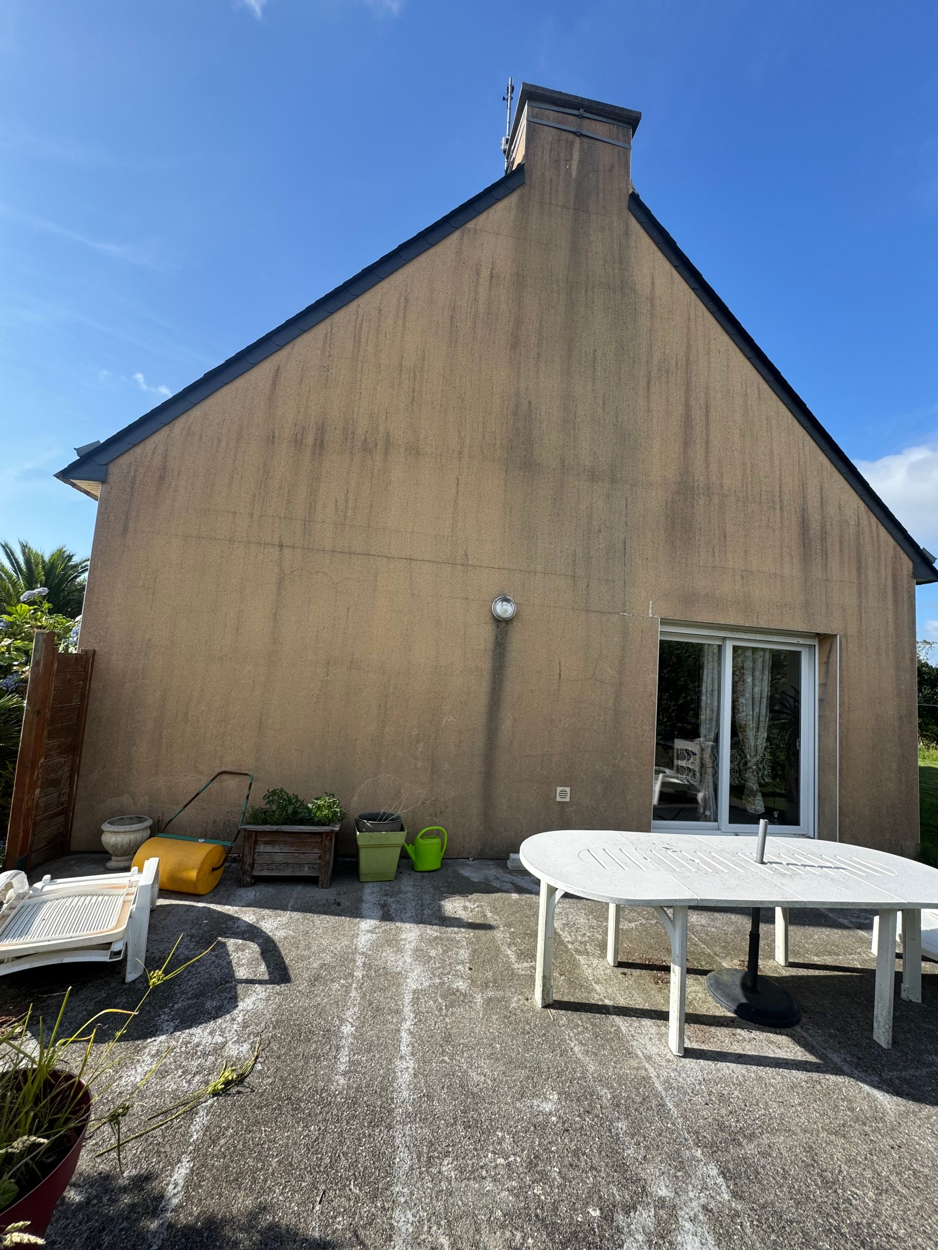 Terrasse arrière attenante à une maison beige.