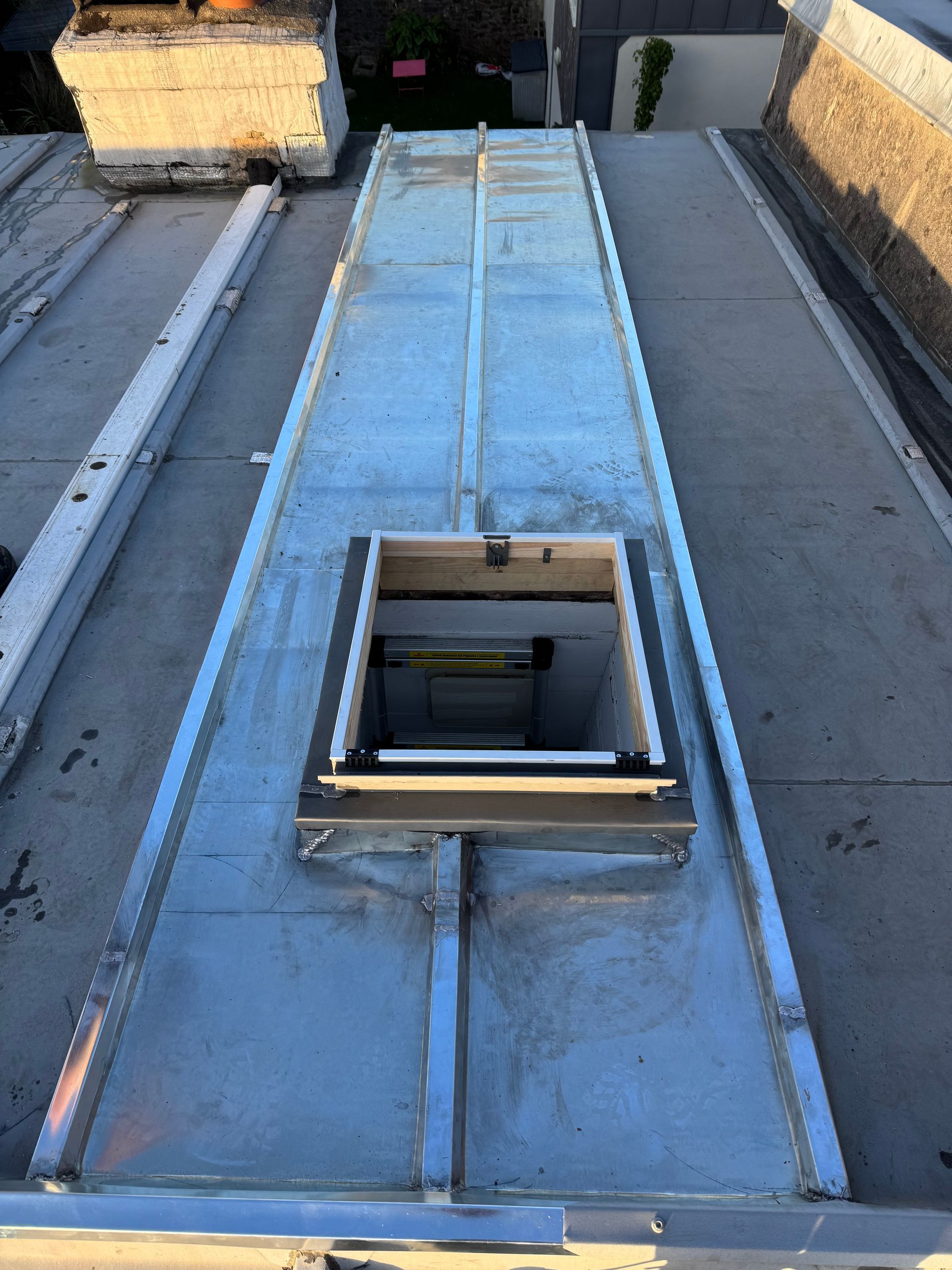 Toit plat recouvert d'une membrane et doté d'une fenêtre de toit carrée.