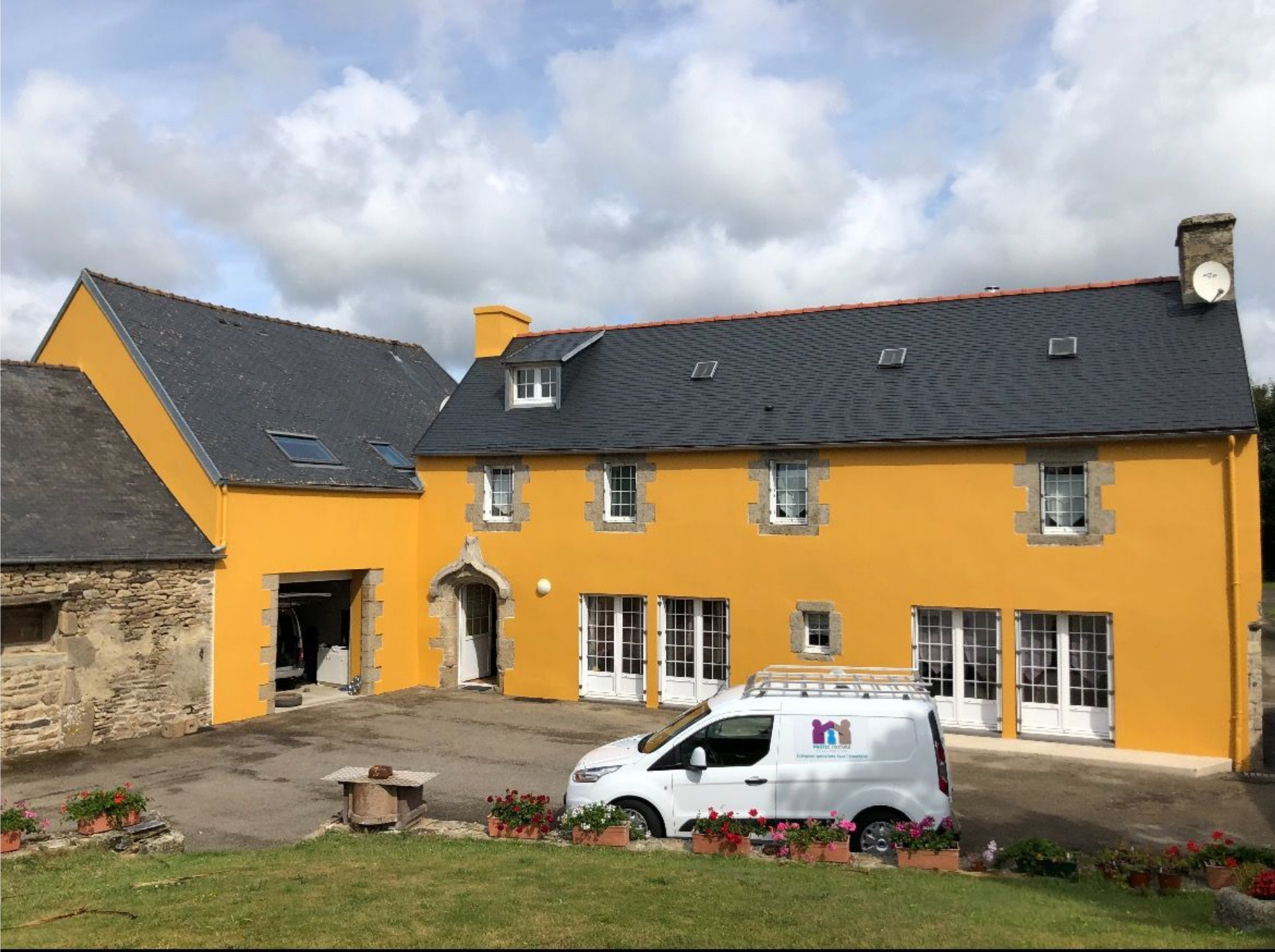 Bâtiment jaune au toit sombre et camionnette blanche garée à l'extérieur.