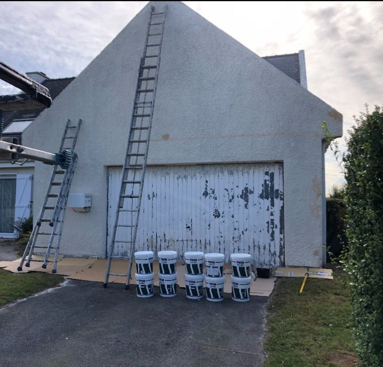 Extérieur d'une grande maison blanche avec des échelles, une nacelle élévatrice surélevée.