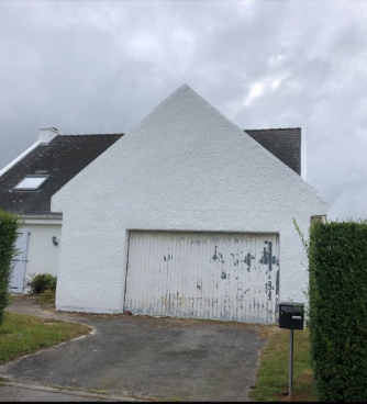 Maison blanche avec une grande porte de garage.