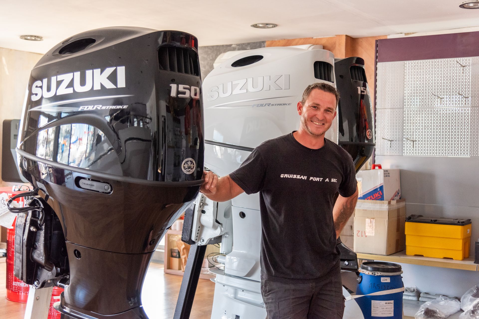 Homme souriant devant un moteur de bateau noir