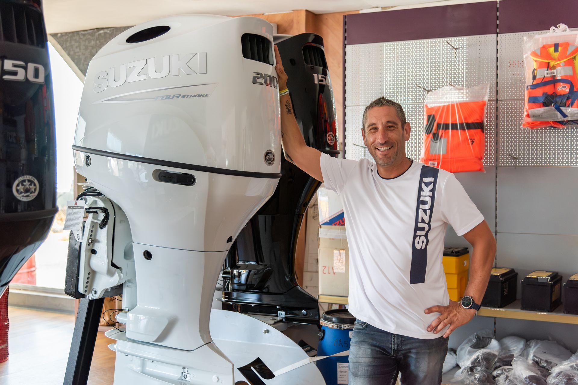 Homme souriant devant un moteur de bateau blanc
