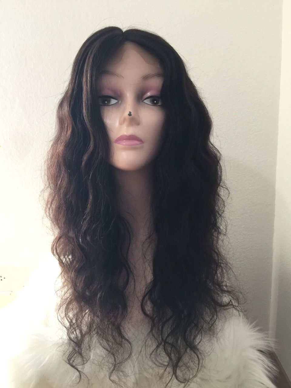 Perücke an einer Schaufensterpuppe mit dunklem, welligem Haar.