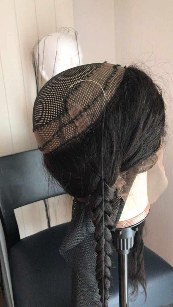Eine Perücke auf einem Ständer mit geflochtenem Schwanz. Zeigt das Innennetz und die Spitzenfront.