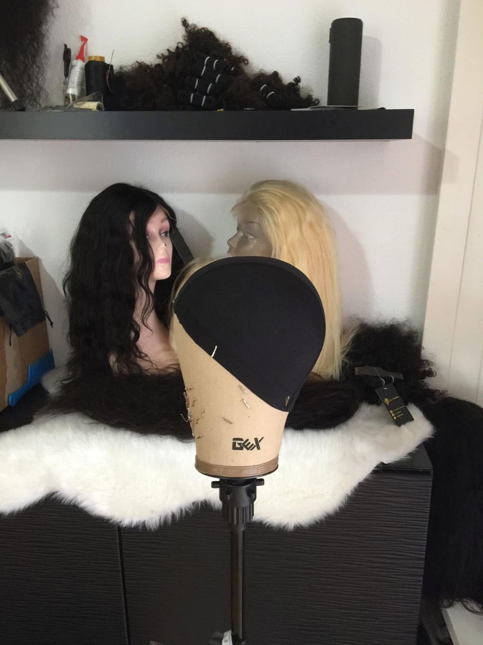 Ein Arbeitsplatz zum Perückenmachen; Perückenkopf im Vordergrund.