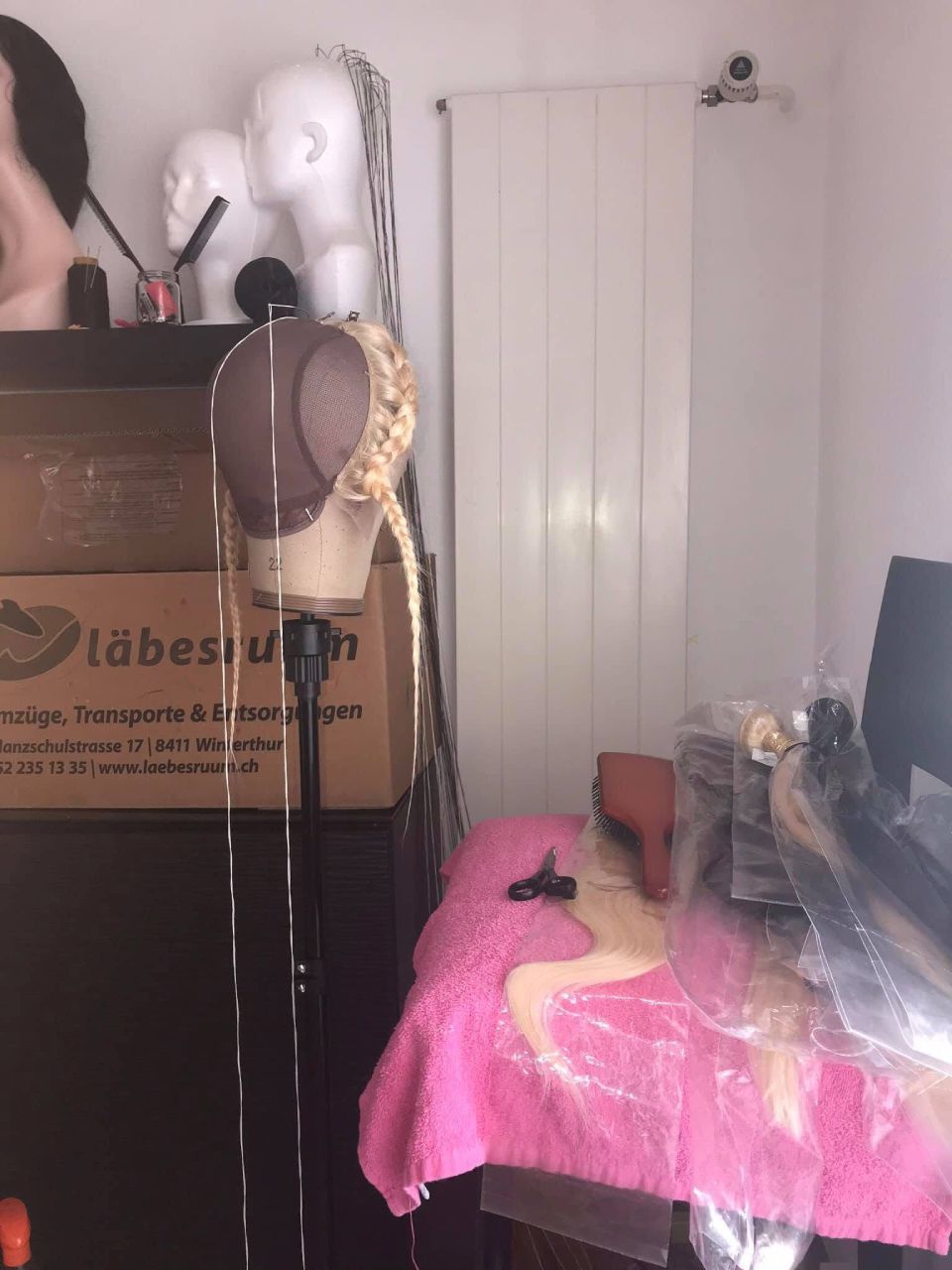 Eine Perückenherstellungsstation mit einem Schaufensterpuppenkopf auf einem Ständer.