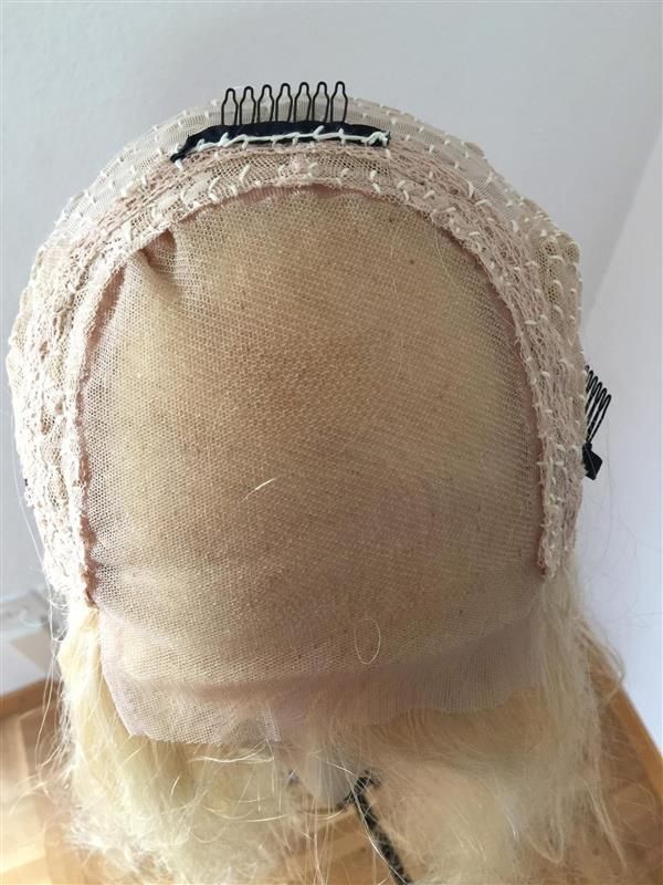 Rückseite einer blonden Perücke mit Kammclips und Netz.