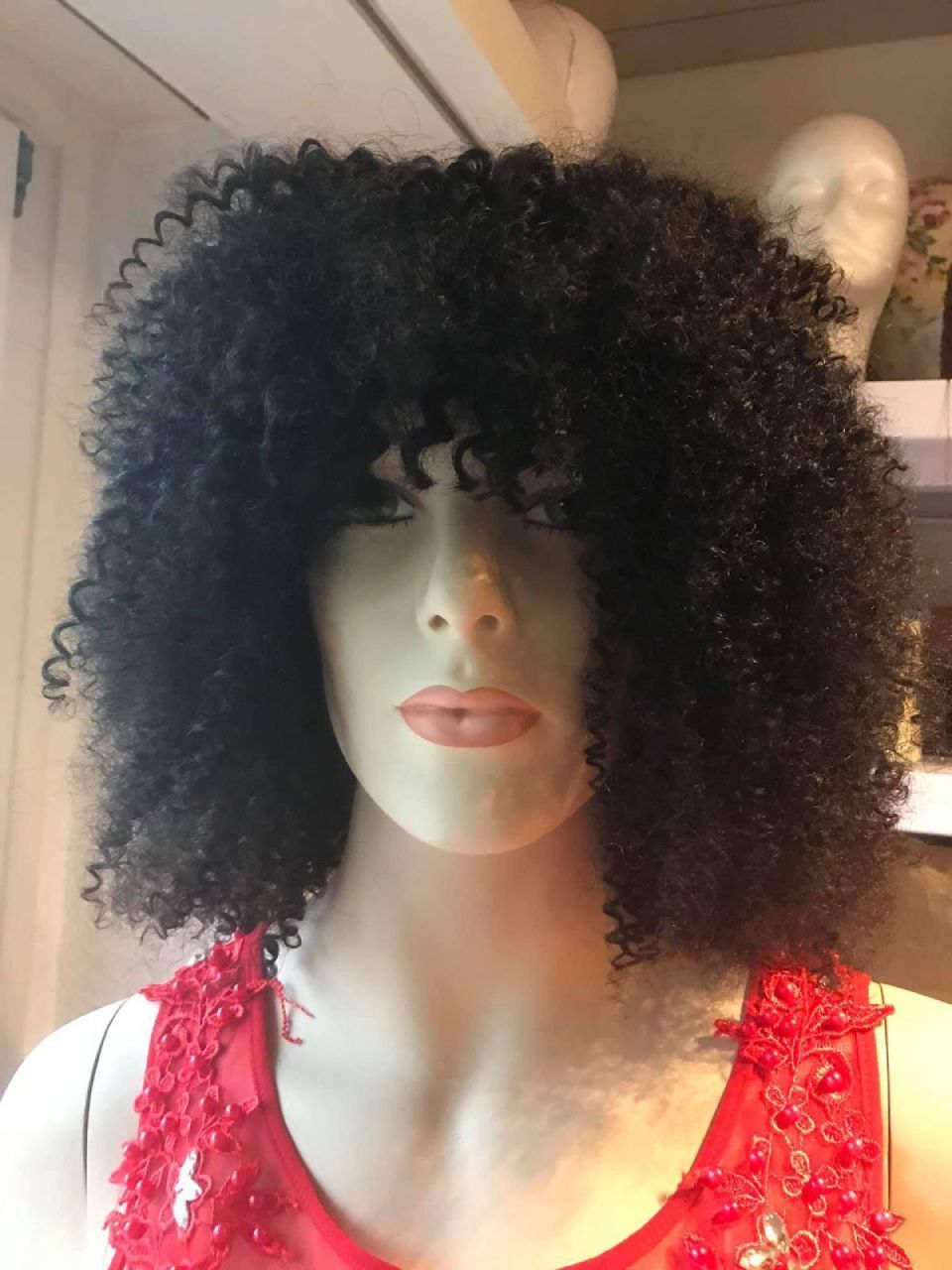 Schaufensterpuppe mit schwarzer Lockenperücke und rotem Kleid.