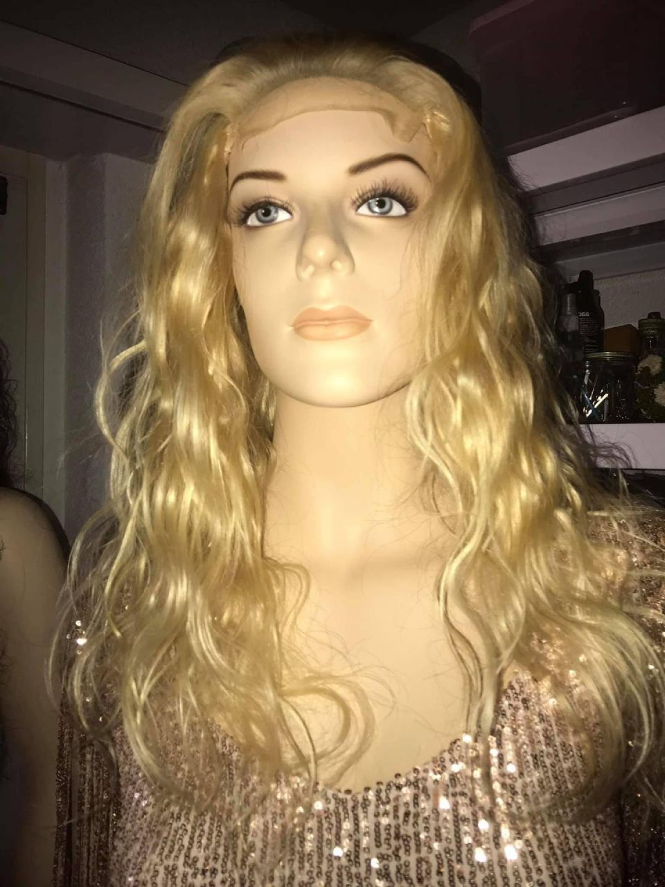 Schaufensterpuppe mit blondem, welligem Haar und einem Oberteil mit Pailletten.