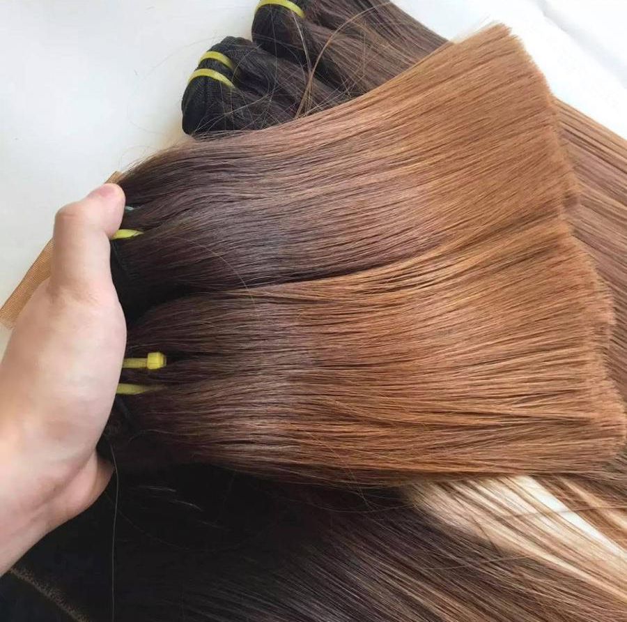 Hand hält Bündel brauner und hellbrauner Haarverlängerungen.