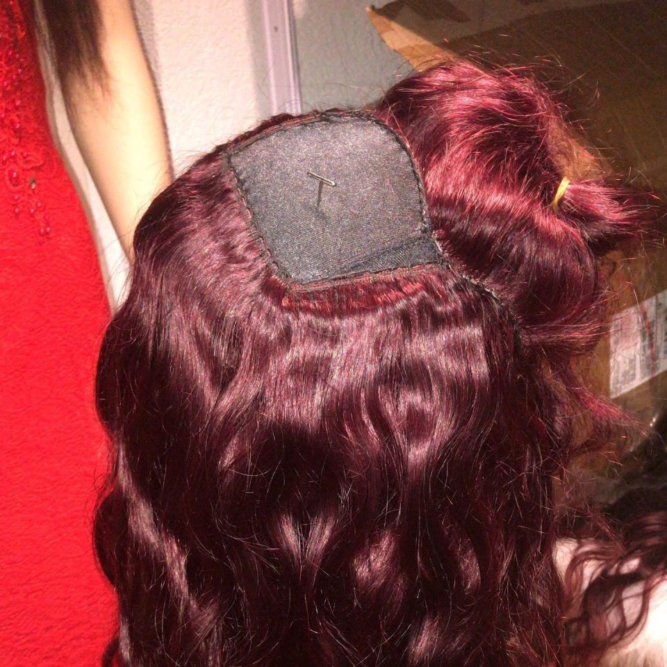 Nahaufnahme einer burgunderfarbenen Perücke mit sichtbar eingenähtem Oberteil.