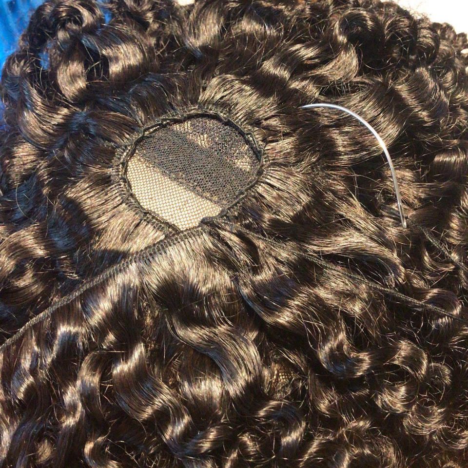 Schwarzes, lockiges Haargeflecht mit einem Netzkreis und einer Nadel.