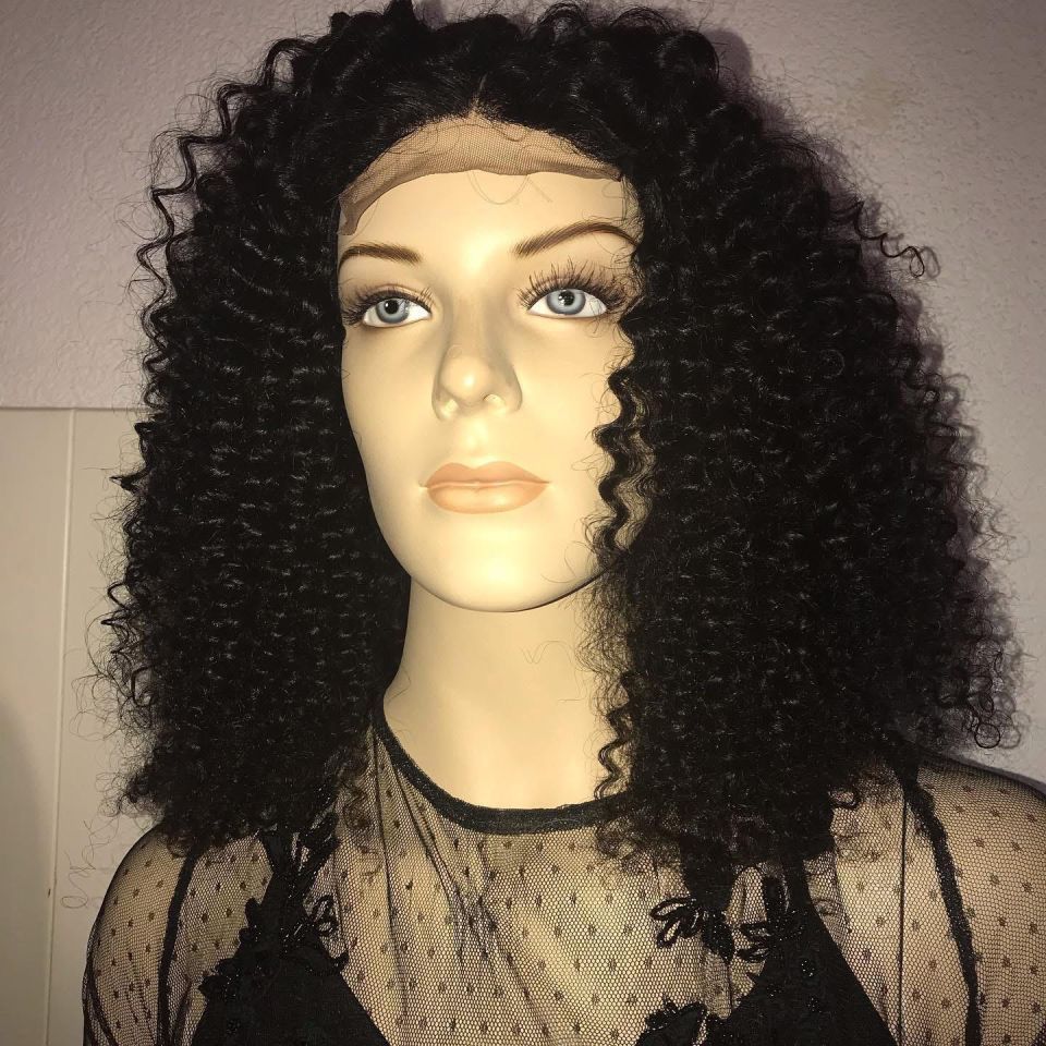 Schaufensterpuppe mit einer lockigen schwarzen Perücke und einem durchsichtigen schwarzen Oberteil.