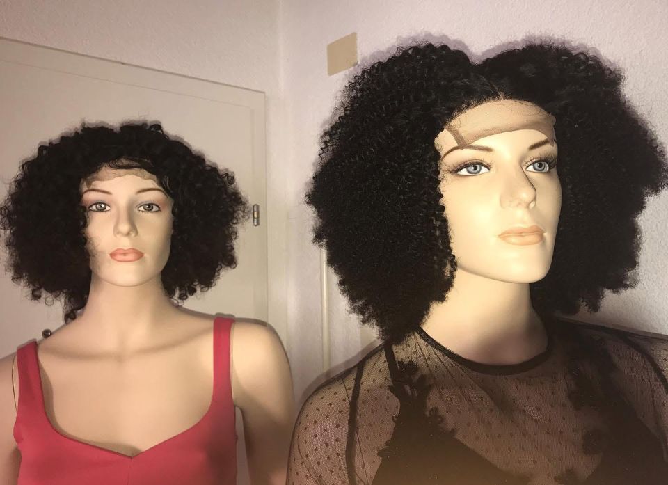 Zwei Schaufensterpuppen mit Afro-Perücken im Innenbereich. Eine trägt ein rotes Tanktop, die andere ein schwarzes Oberteil.