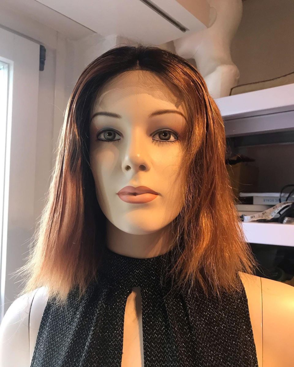 Schaufensterpuppe mit Perücke, braunem Haar, Mittelscheitel und schwarzem, schimmerndem Oberteil.