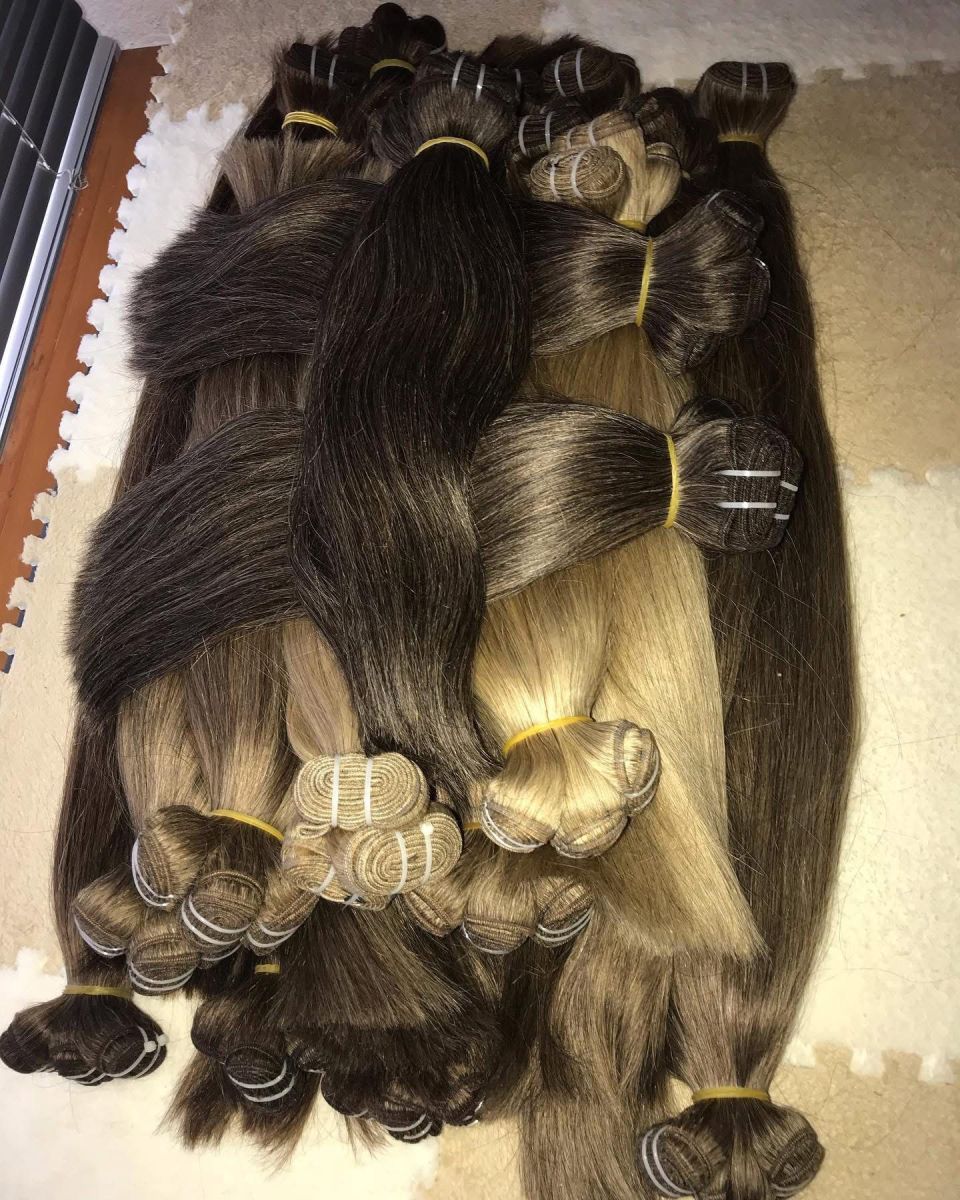 Bündel aus braunen, schwarzen und blonden Haarverlängerungen, mit Gummibändern zusammengebunden.