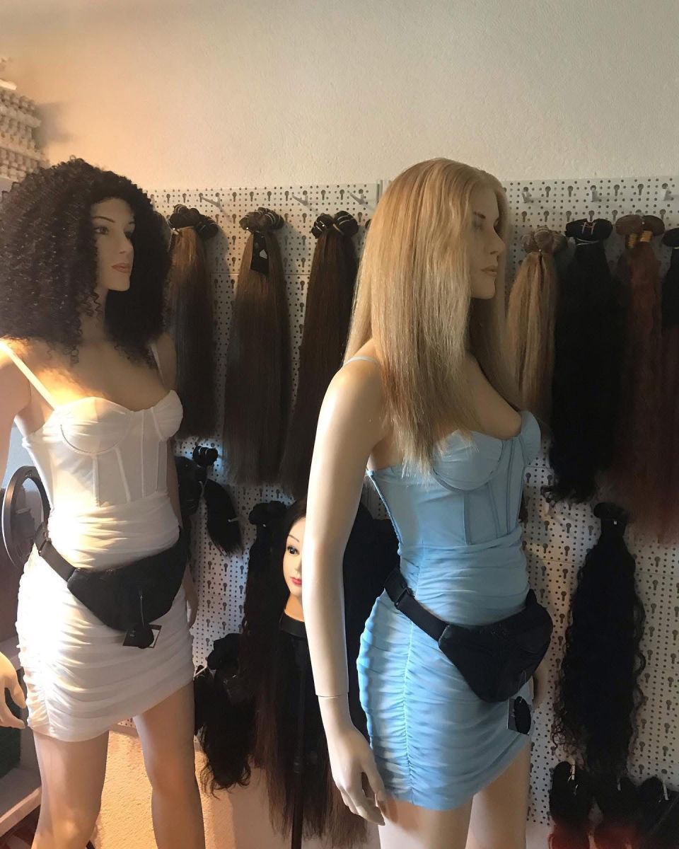 Zwei Schaufensterpuppen tragen Kleider und Gürteltaschen, dahinter sind Haarverlängerungen ausgestellt.