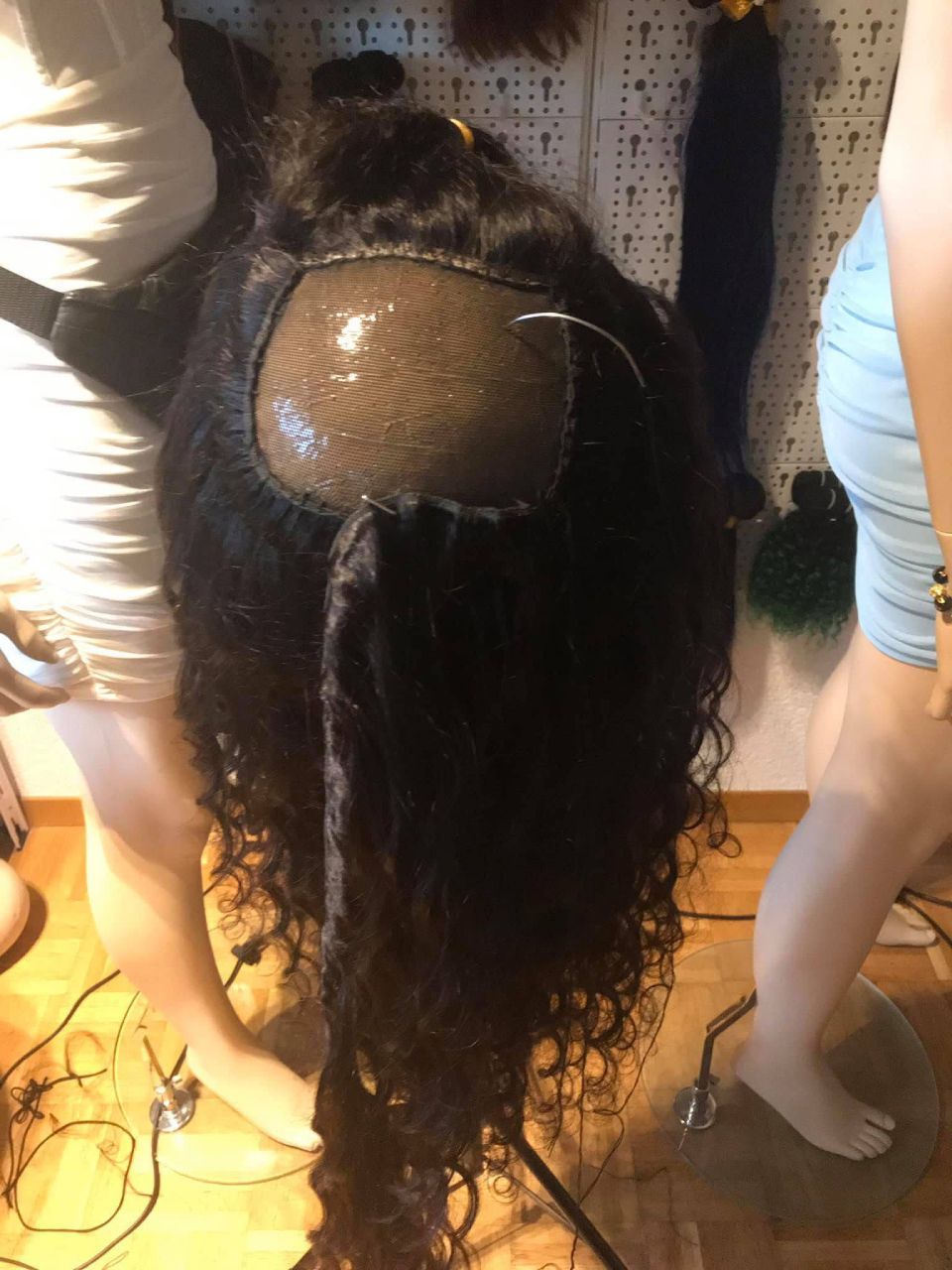 Eine dunkle, gelockte Webkappe wird hergestellt; zwei Personen arbeiten daran.