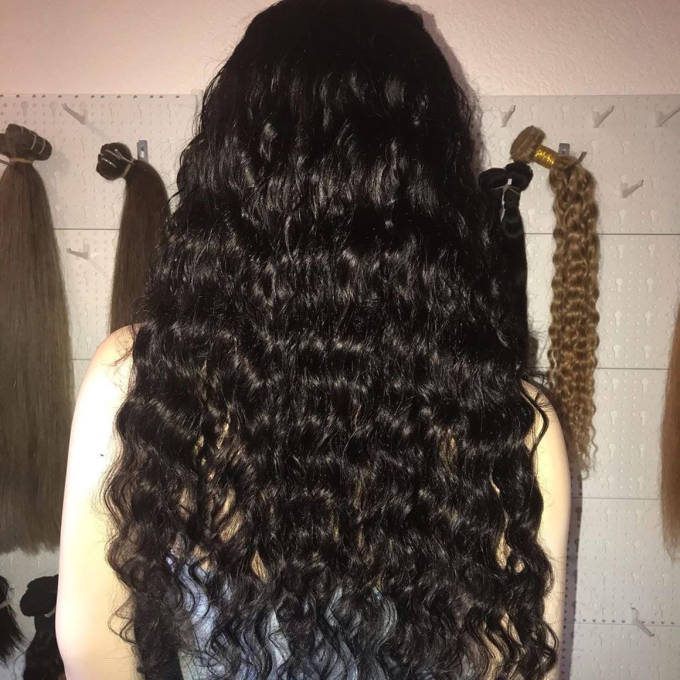 Frau mit langen, welligen, schwarzen Haaren; im Hintergrund Produkte an Haken.