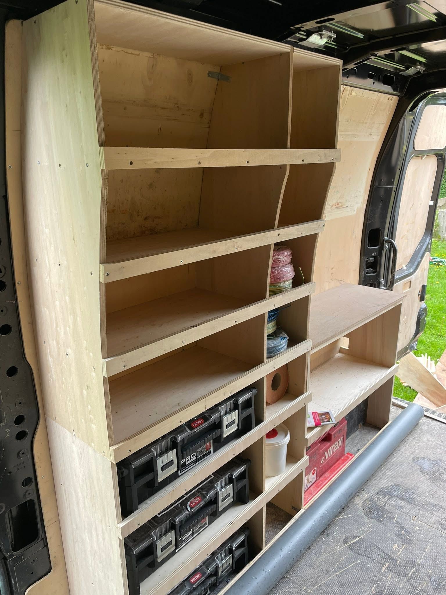 Étagère en bois avec des compartiments vides et du matériel audio empilé dans l'intérieur d'un véhicule