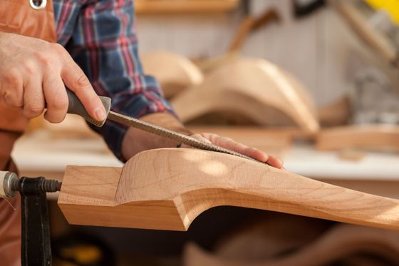 Main utilisant une râpe pour façonner une pièce de bois dans un atelier