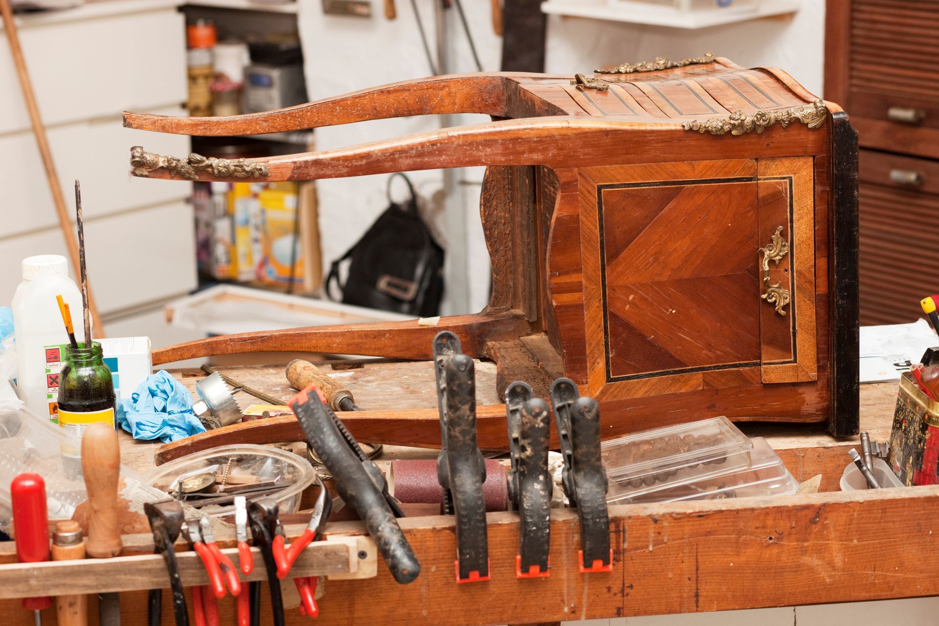 Maquette de meuble en bois sur un établi encombré d'outils et de serre-joints.