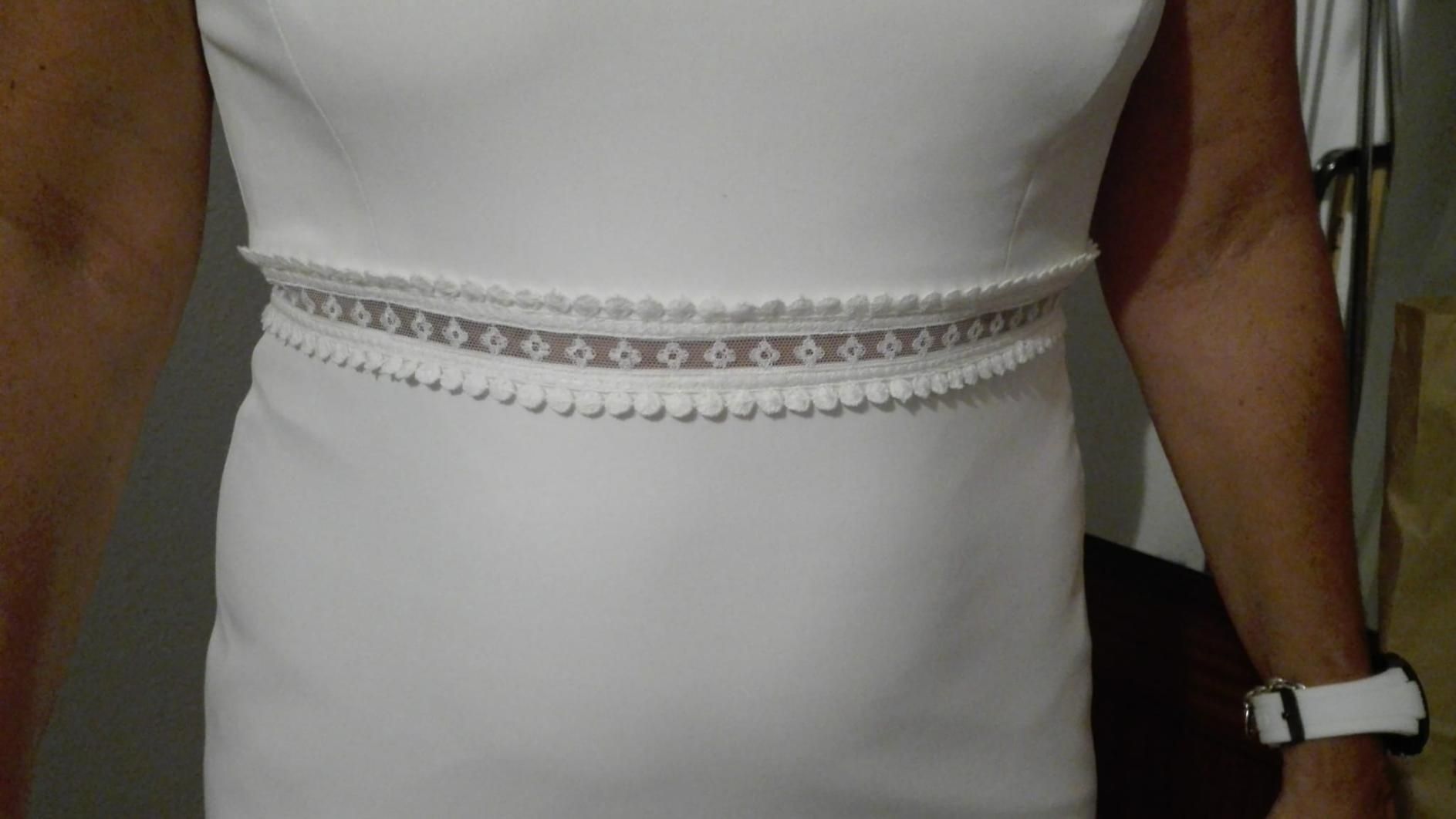 Mujer con vestido blanco y cinturón blanco decorativo.