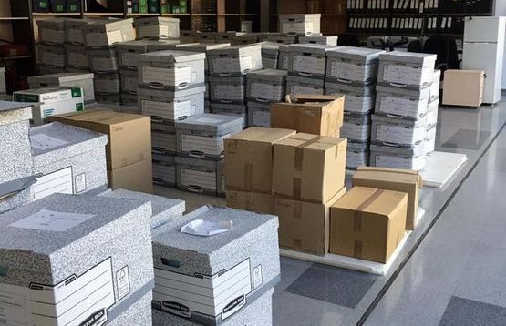 Cajas apiladas en un almacén. Cajas de cartón gris y marrón sobre un suelo brillante.