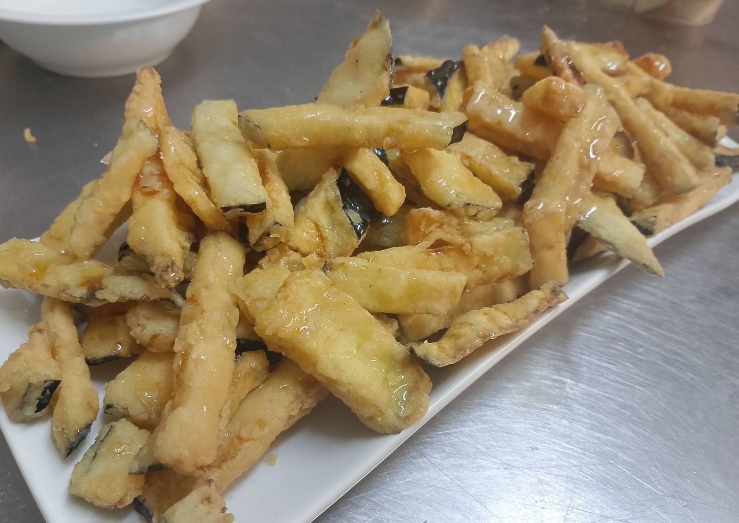 Un plato blanco cubierto con verduras fritas sobre una mesa.