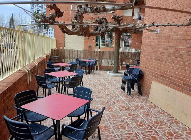 Un patio con mesas y sillas frente a un edificio de ladrillo.