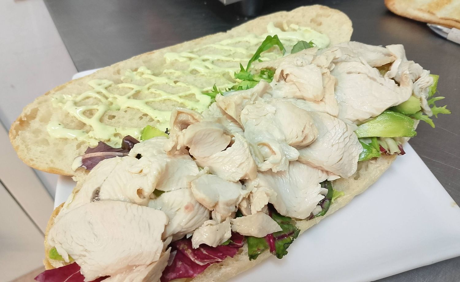 Un sándwich con pollo y lechuga en un plato blanco.