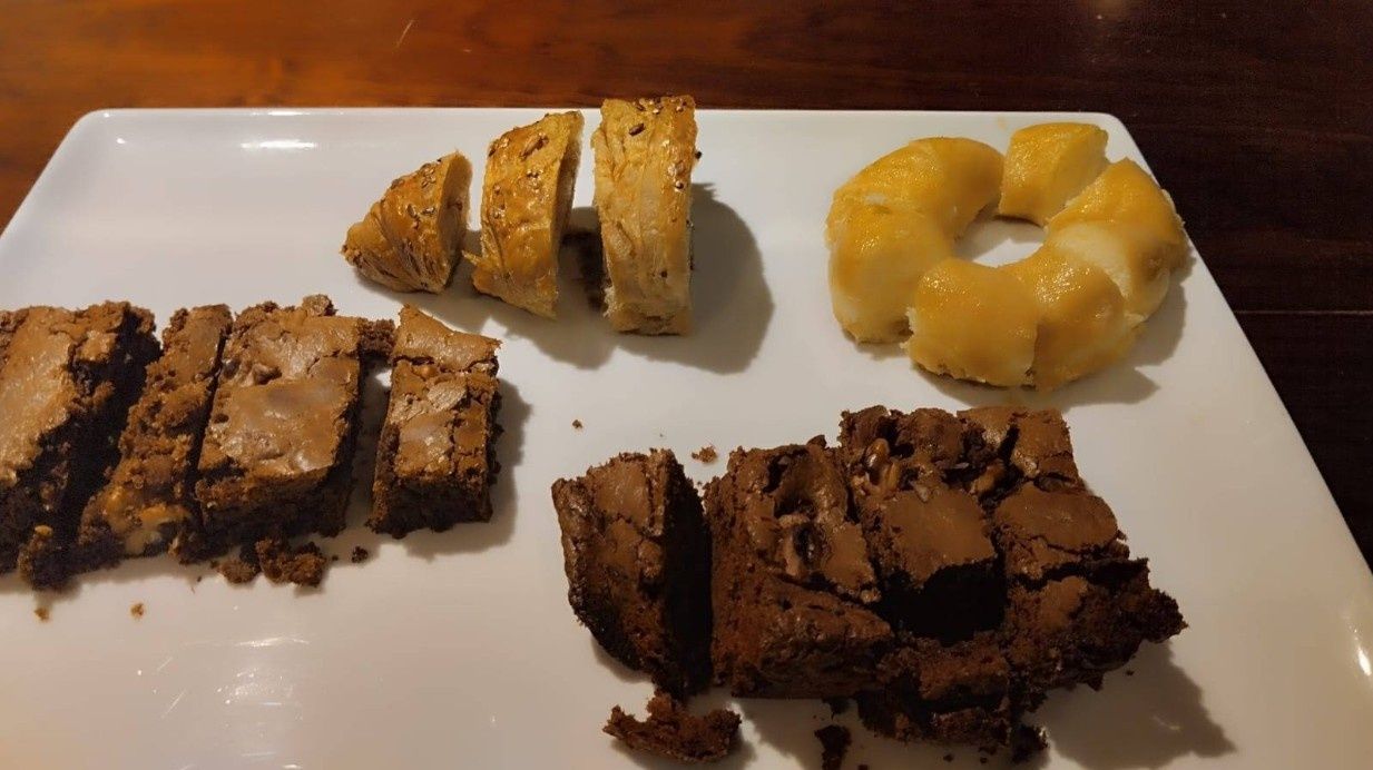 Un plato blanco cubierto con brownies y una dona de piña.
