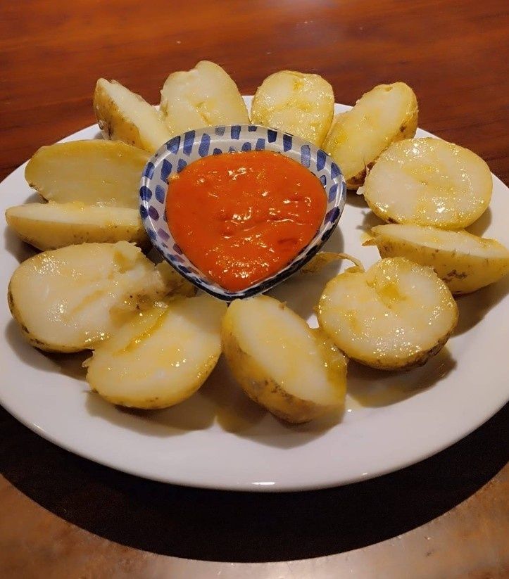 Un plato blanco cubierto con patatas y un tazón pequeño de salsa.