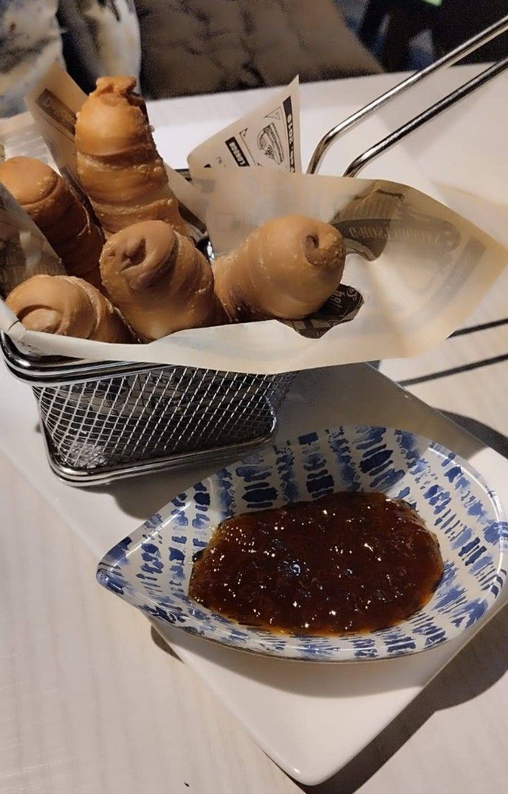 Una canasta de comida junto a un plato de salsa para mojar