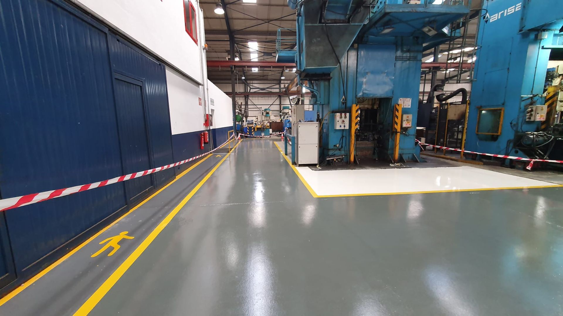 Un gran almacén con mucha maquinaria y una línea amarilla en el suelo.