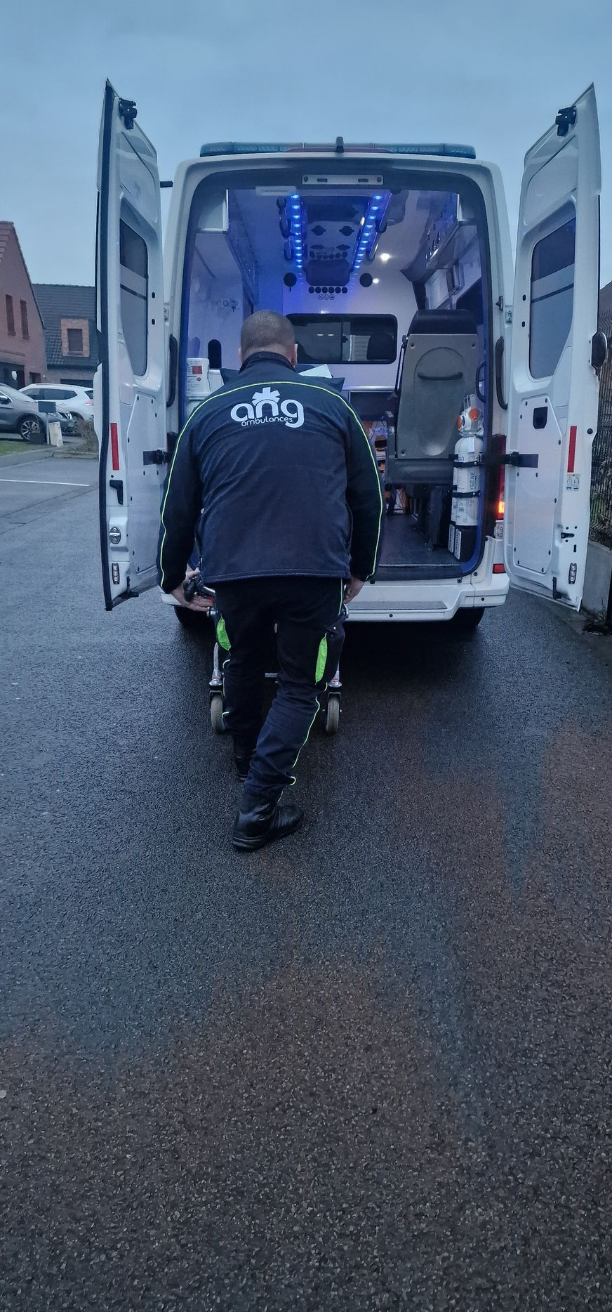 Ambulancier devant un véhicule avec les portes ouvertes.