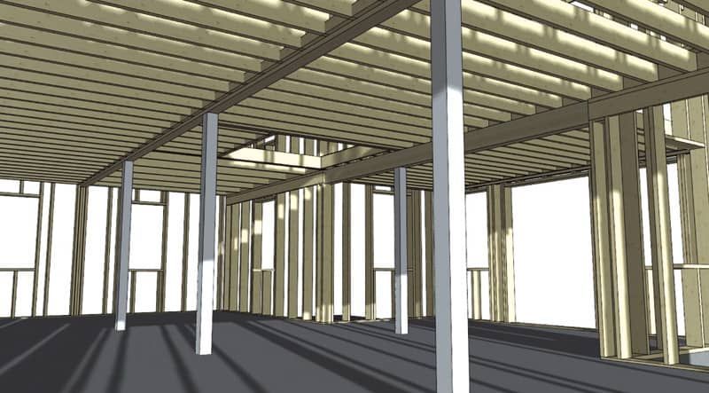 Interior view of a building under construction, with wooden framing and support columns.