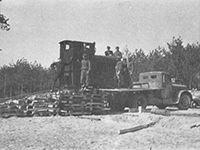 Ein Schwarzweißfoto eines mit Baumstämmen beladenen Lastwagens.