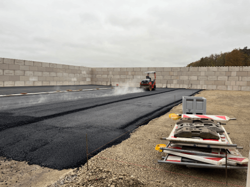 Ein Traktor verlegt Asphalt auf einer Baustelle.