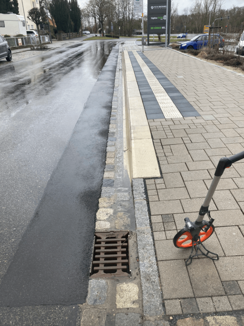 Ein Messrad steht auf dem Bürgersteig neben einem Abfluss