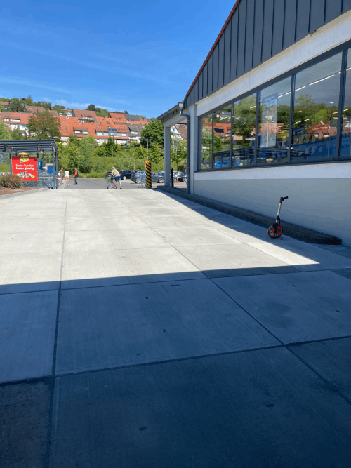 An einem sonnigen Tag parkt ein Roller vor einem Gebäude