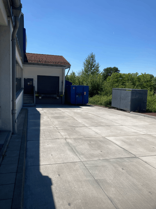 Ein Gebäude mit einem blauen Müllcontainer davor