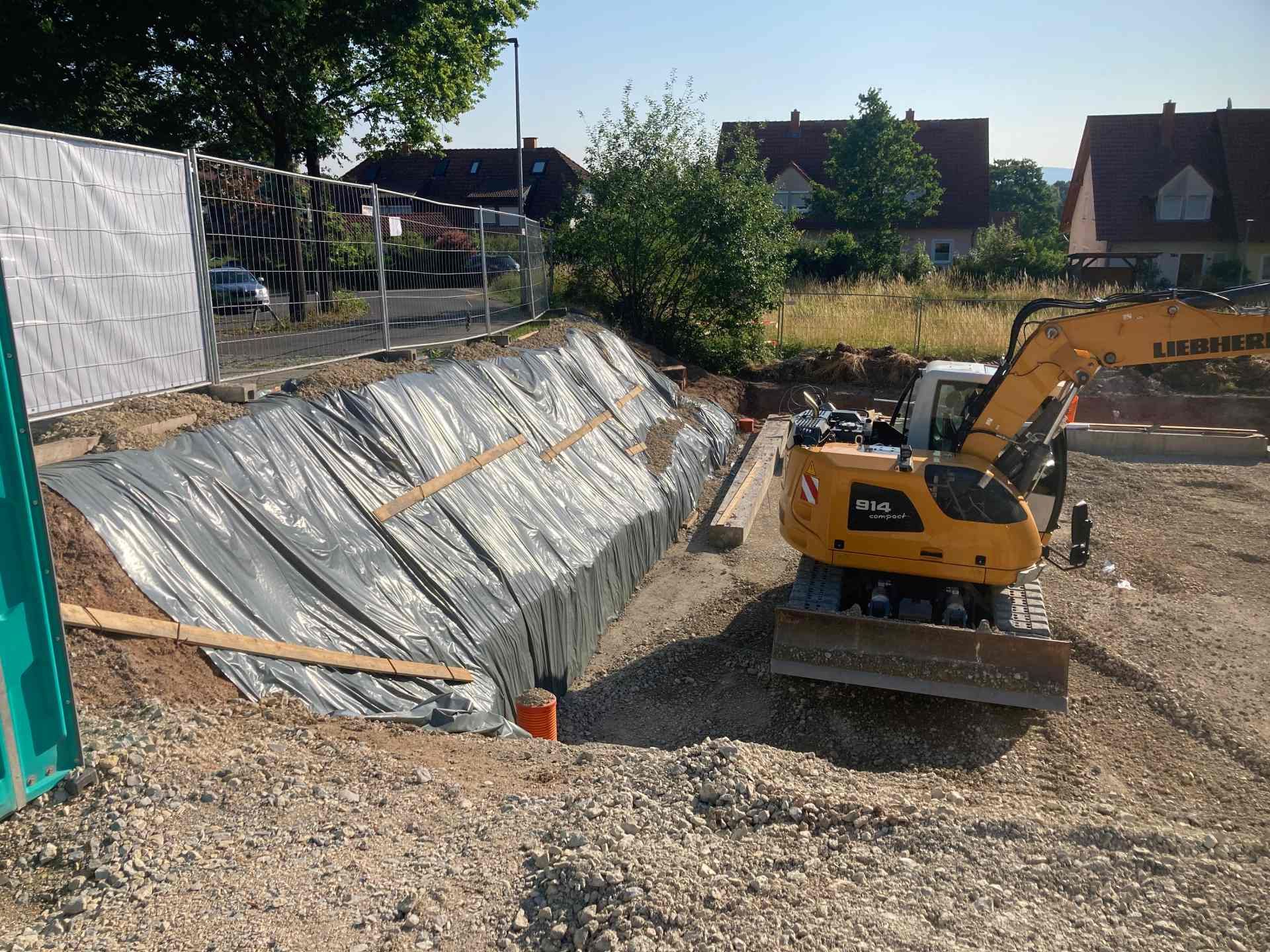 Ein gelber Bagger arbeitet auf einer Baustelle.
