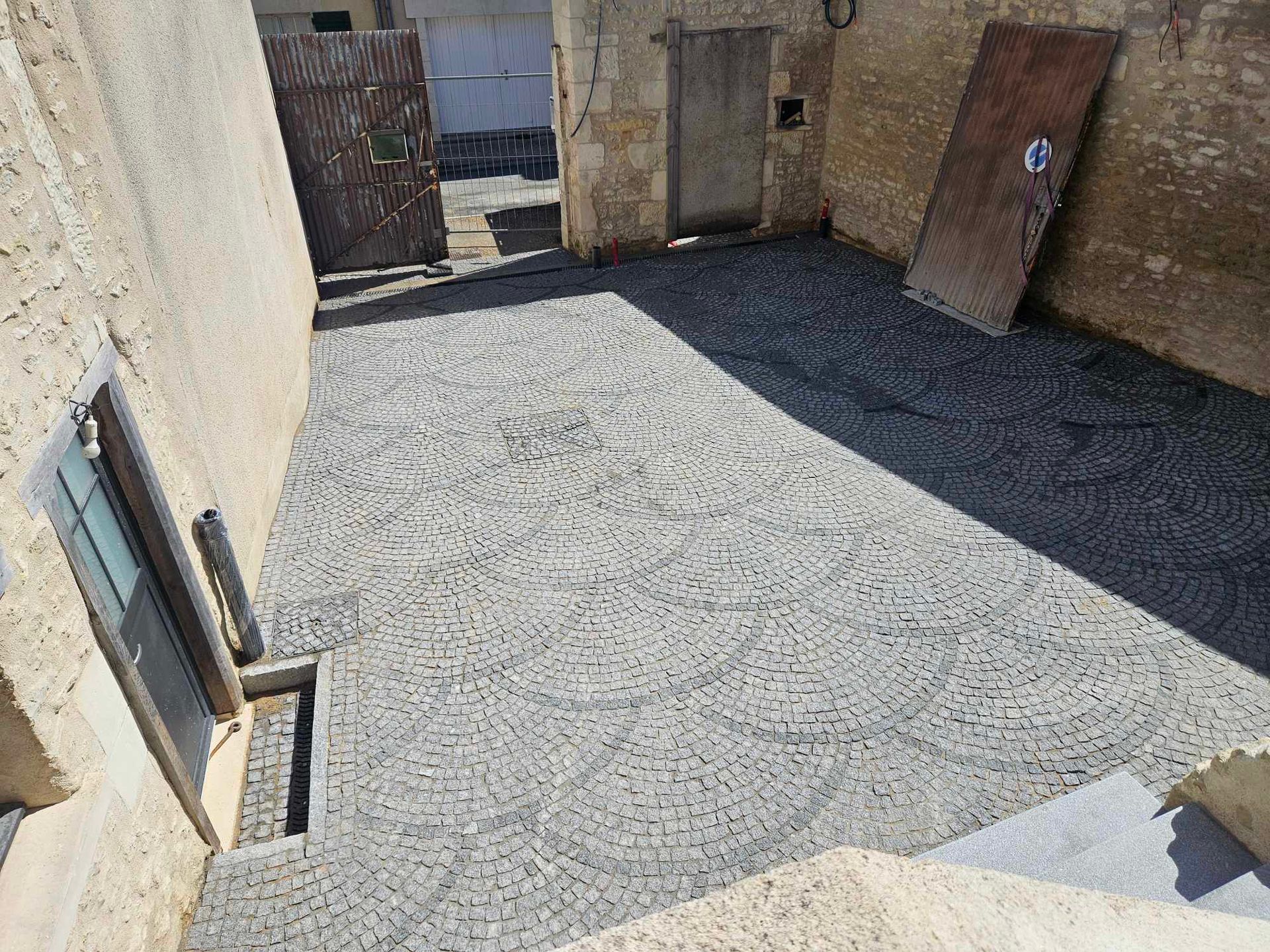 Cour pavée avec portes, murs et une fenêtre.