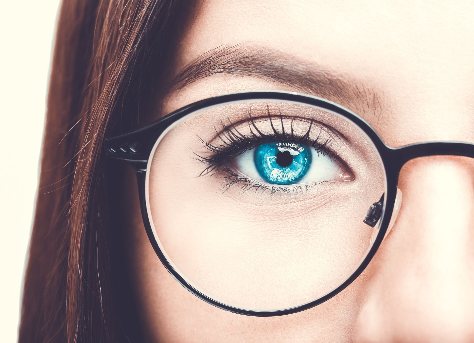 Un primer plano del ojo azul de una mujer con gafas.